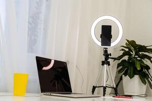 laptop, lamp and tripod on the table for online interview photo