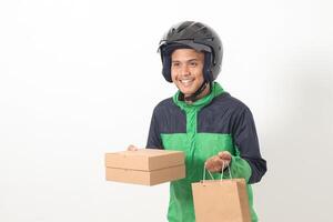 Portrait of Asian online courier driver wearing green jacket and helmet delivering package and box for customer. Isolated image on white background photo