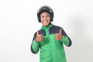 Portrait of Asian online taxi driver wearing green jacket and helmet showing good job sign, thumb up. Isolated image on white background photo