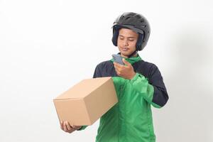Portrait of Asian online taxi driver wearing green jacket and helmet holding a box and scanning or capturing the package. Isolated image on white background photo