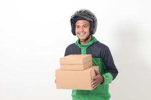 Portrait of Asian online courier driver wearing green jacket and helmet delivering package and box for customer. Isolated image on white background photo