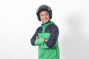 Portrait of Asian online taxi driver wearing green jacket and helmet, standing with crossed arms. Isolated image on white background photo