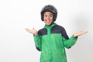 Portrait of Asian online taxi driver wearing green jacket and helmet choosing between 2 different options, holding two hands with empty space. Isolated image on white background photo