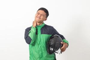 Portrait of tired Asian online taxi driver wearing green jacket holding a helmet on hip and feeling exhausted. Isolated image on white background photo