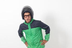 Portrait of tired Asian online taxi driver wearing green jacket and helmet doing weird funny pose. Isolated image on white background photo