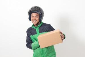 Portrait of Asian online courier driver wearing green jacket and helmet delivering package and box for customer. Isolated image on white background photo