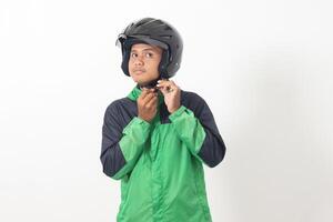 Portrait of Asian online taxi driver wearing green jacket and helmet demonstrating how to wear helmet correctly. Isolated image on white background photo