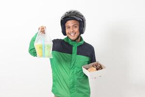 Portrait of Asian online taxi driver wearing green jacket and helmet holding a box of donuts and cup of juice drink, delivering to customer. Isolated image on white background photo