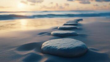 Stepping grey stones with texture forwarding in beach sand and ocean water with blue sky photo