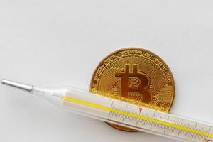 Mercury thermometer and bitcoin on white background photo