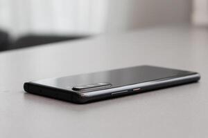 Black modern mobile phone with blank screen on black stone table background. Smartphone on old dark grey vintage texture background. photo