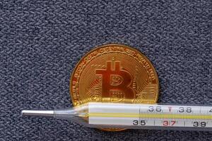 Mercury thermometer and bitcoin on white background photo