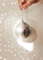 Close-up of a hand holding a disco ball, casting reflections and light patterns on the background photo