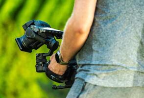 Filmmaker Capturing Outdoor Footage With Camera Gear During Golden Hour in a Natural Setting photo