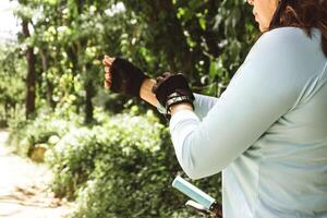 horizontal photograph of an unrecognizable woman adjusting her shirt and gloves to ride a bicycle. mountain biking concept. photo