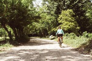 horizontal shot from behind of a female cyclist riding a bicycle running on a dirt road. mountain bike concept. photo
