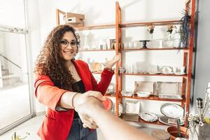 first person view of a woman greeting and meeting a customer while showing him a rack of event items photo