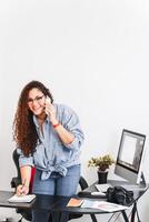 Young Latin American entrepreneur making notes in a notebook while making a phone call. photo