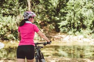 horizontal photograph of a professional cyclist woman with her back turned walking and holding a bicycle. freedom and exercise concept. photo