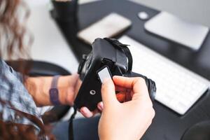 Hands of a person holding a camera and inserting a memory card. photo