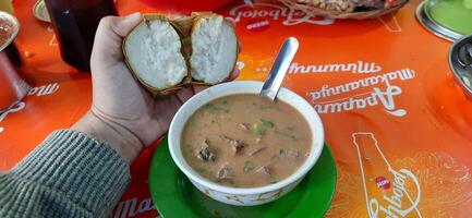 Coto Makassar or Coto Mangkasarak, traditional food from Makassar. Served in a bowl filled with offal and meat and enjoyed with ketupat. Makassar, South Sulawesi, Indonesia - August 31 2024 photo