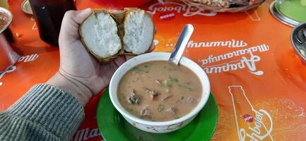 Coto Makassar or Coto Mangkasarak, traditional food from Makassar. Served in a bowl filled with offal and meat and enjoyed with ketupat. Makassar, South Sulawesi, Indonesia - August 31 2024 photo