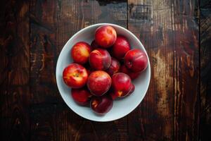 A bowl of plums on a wooden table photo