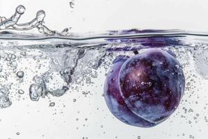 A purple plum is floating in water with bubbles photo