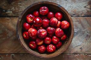 A bowl of red plums on a wooden table photo