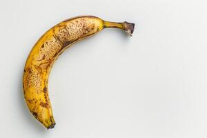 A banana with brown spots on it is shown photo