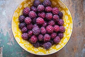 A bowl of raspberries on a wooden table photo