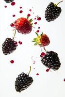 Blackberries and strawberries falling into water photo