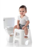 A baby sitting on a stool next to a toilet photo