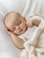 A baby sleeping in a white blanket photo