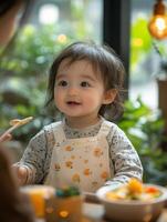 A baby girl sitting at a table with a bowl of food photo