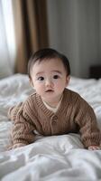 A baby in a sweater laying on a bed photo