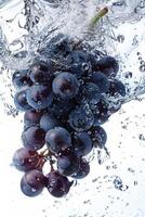 A bunch of grapes is being splashed into the water photo