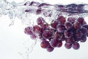A bunch of grapes is being splashed into the water photo