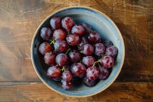 A bowl of grapes on a wooden table photo