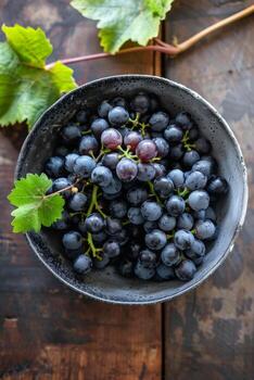 A bowl of grapes on a wooden table photo
