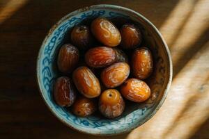 A bowl of dates on a wooden table photo