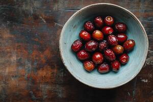 A bowl of dates on a wooden table photo