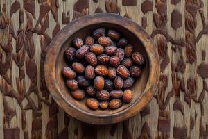 A bowl of dates on a wooden surface photo
