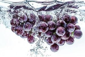 A bunch of grapes is being splashed into the water photo