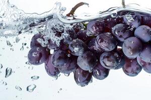 A bunch of grapes is being splashed into the water photo