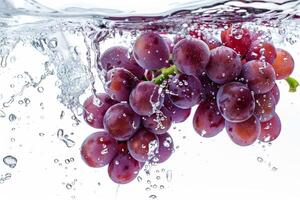 A bunch of grapes is being splashed into the water photo