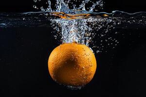 An orange is being dropped into water photo