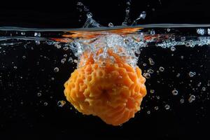 An orange fruit is being splashed into the water photo