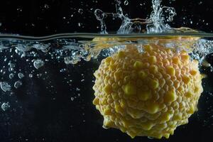 A yellow fruit is being splashed in water photo