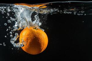Orange falling into water with bubbles photo